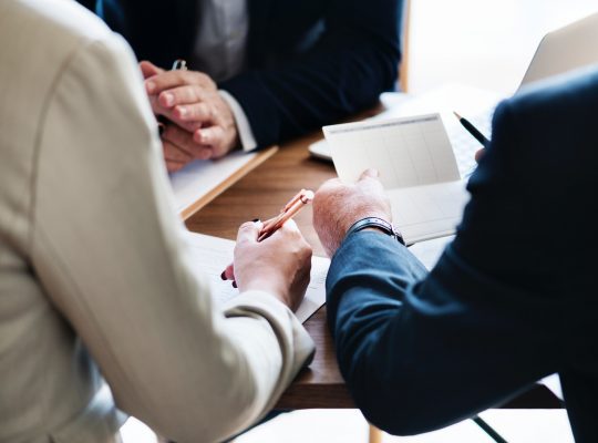 Un groupe de personnes est attablé : elles travaillent ensemble sur des dossiers papiers