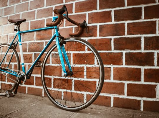 Un vélo bleu sur un mur en brique