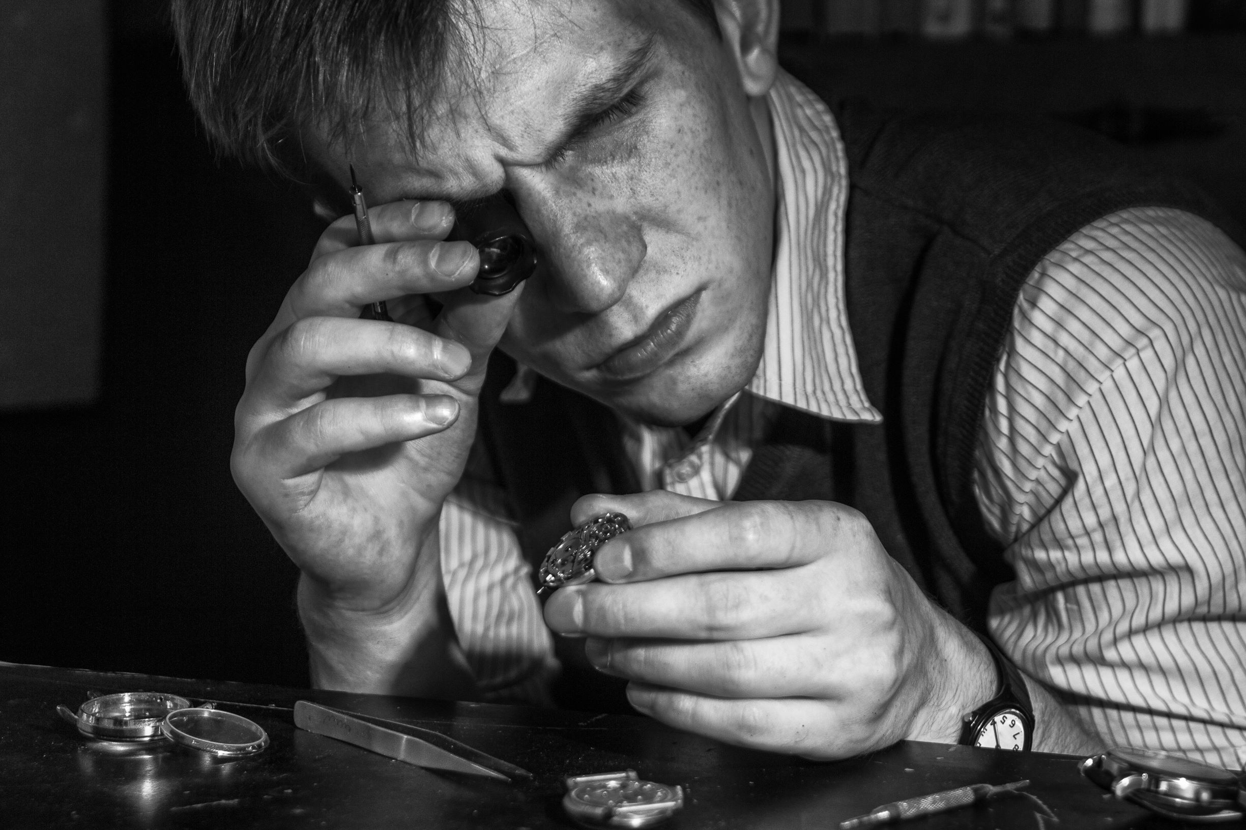 Une personne avec une loupe de joaillier regarde une bijoux afin de l'estimer