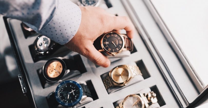 Un homme range une montre dans un coffret avec d'autres montres