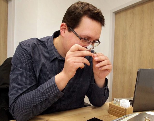 Une personne avec une loupe de joaillier regarde une bague afin de l'estimer