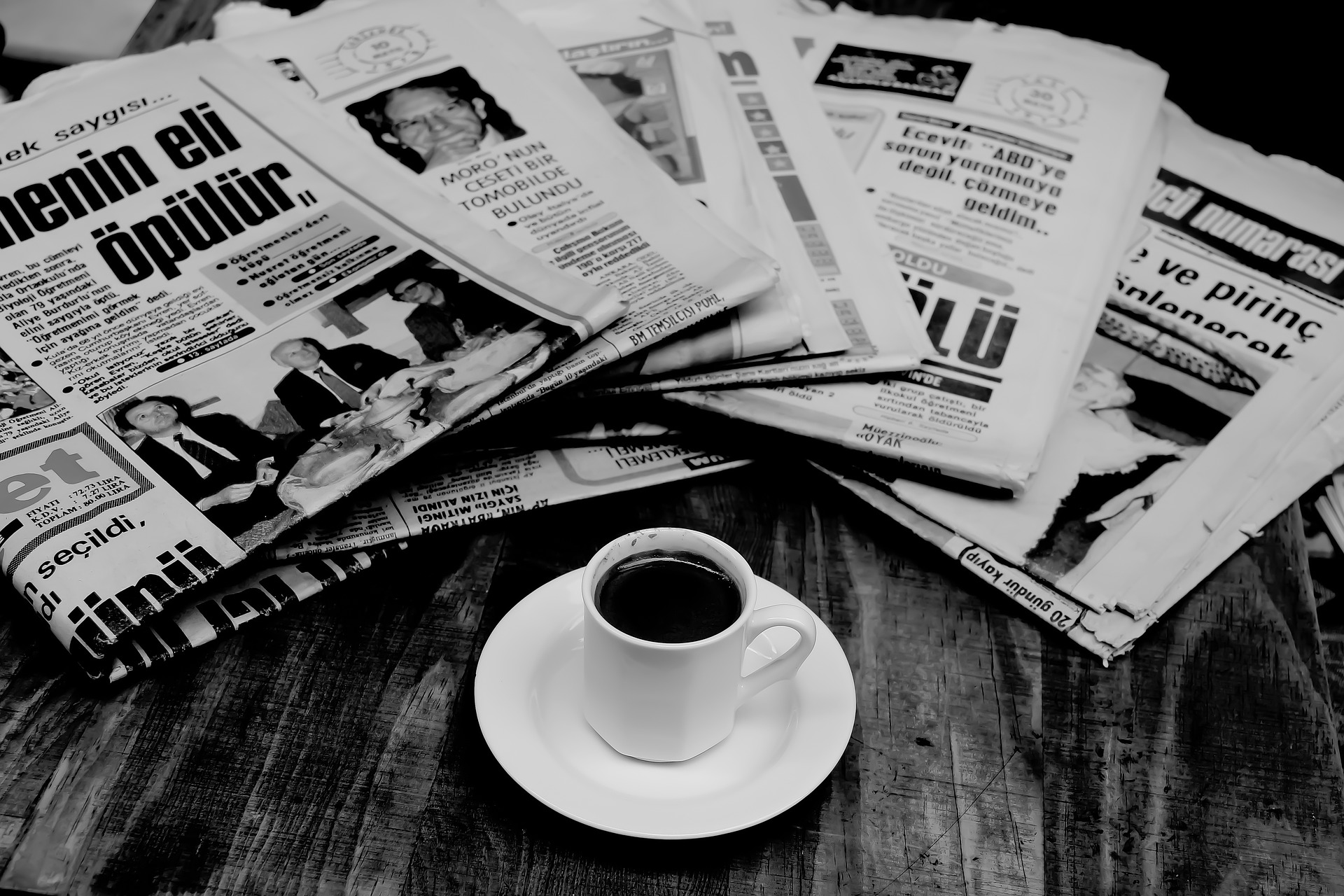 Sur une table, un café avec un éventail de journaux