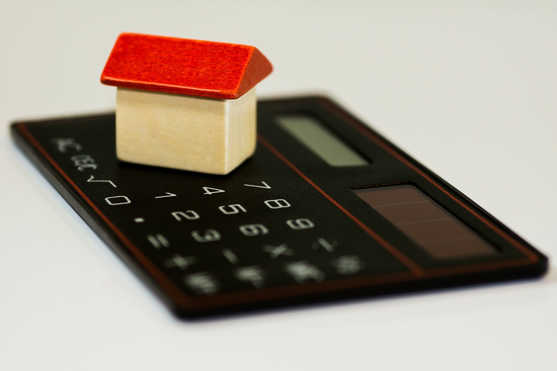 Une calculatrice noire sur laquelle est posée une petite maison de bois