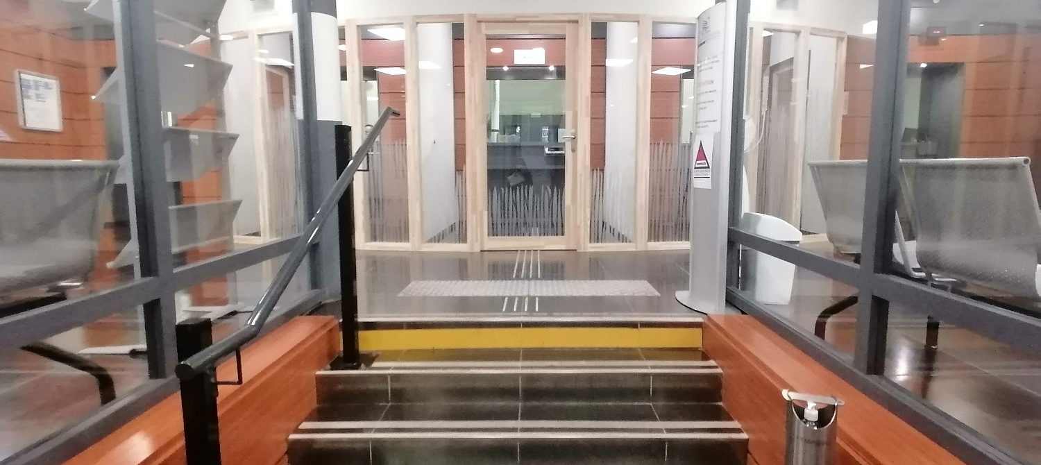 L'entrée du Crédit Municipal de Toulouse : au premier plan les escalier puis au second plan les guichets aux portes transparentes et encadrementsen bois clair