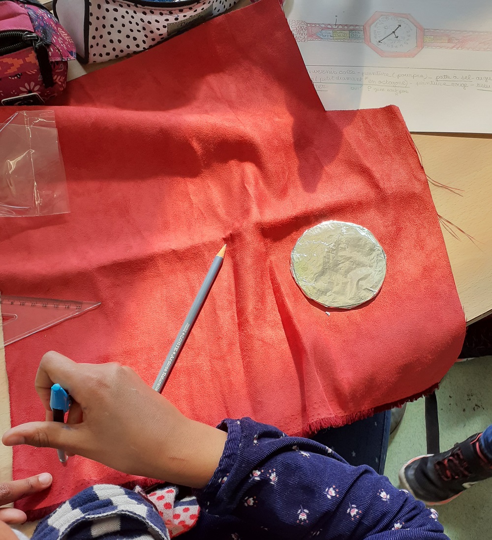 Passeport pour l'art : Une élève travaille sur un tissu rouge et utilise, crayon, équerre et gabarit d'un cercle