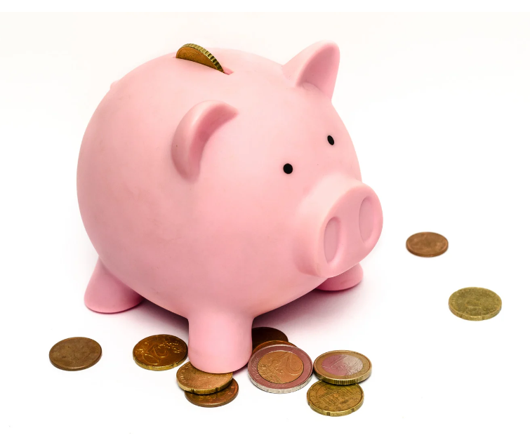 Une tirelire en forme de cochon de couleur rose avec sous ses pates des pièces de monnaie et une dans sa fente