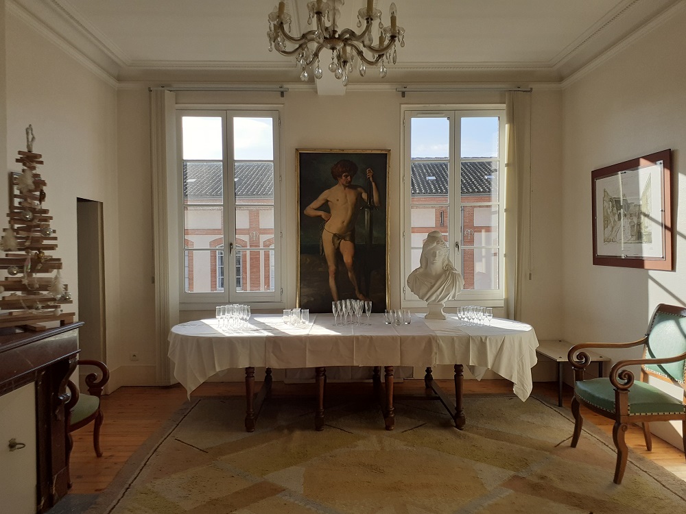 La salle pour les voeux : sur la gauche un sapin en bois, au centre une table sur laquelle sont posés les verres et le buste de Marianne, en arrière plan un tableau d'un homme encadré par deux fênetres