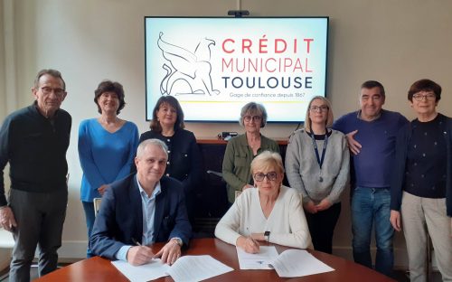 AGIR abcd et le Crédit Municipal ensemble pour la finance solidaire Les bénévoles d'AGIRabcd, l'agente du Crédit Municipal debout dérrière le directeur de l'établissement et la présidente de l'association signant la convention de partenariat